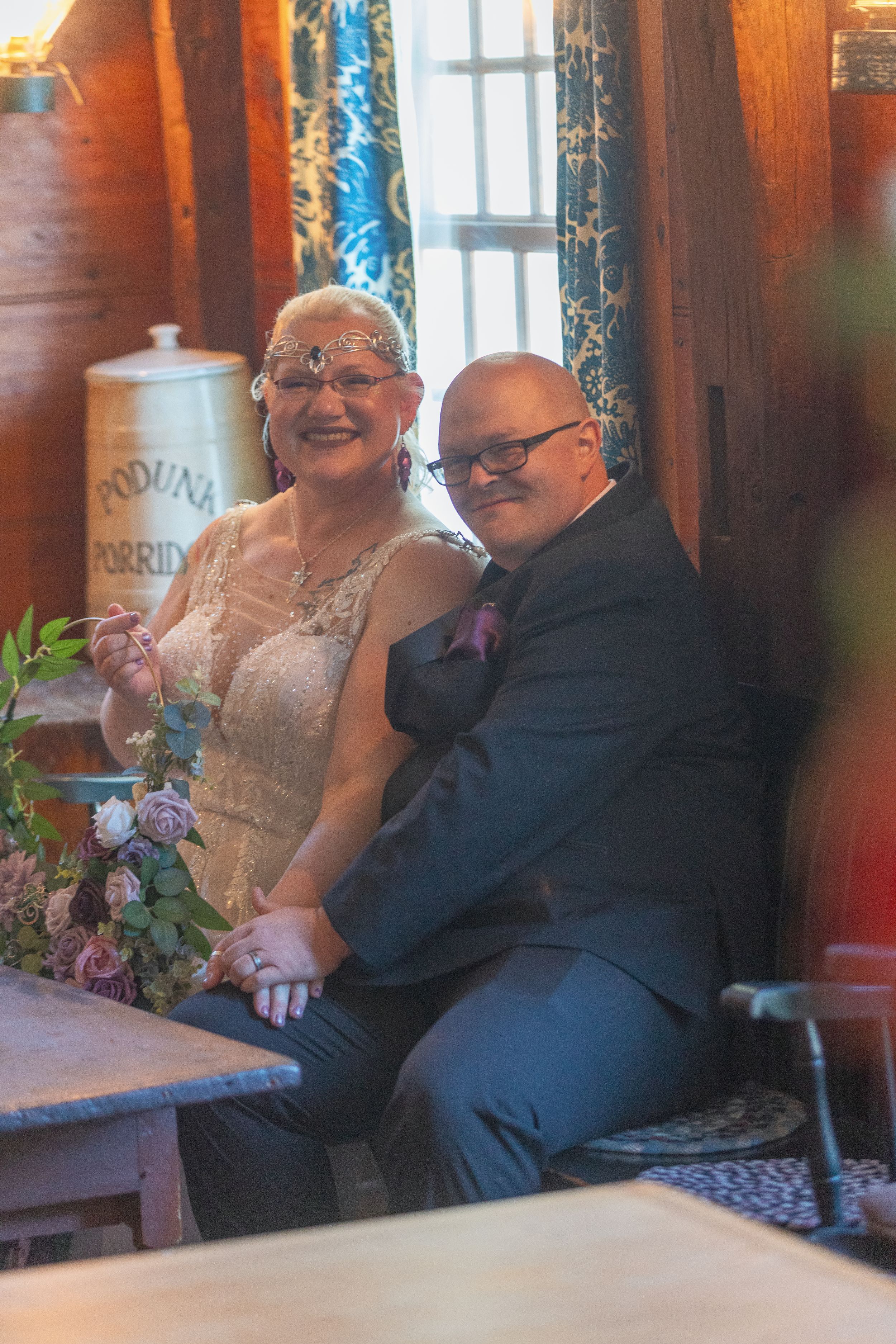 A couple shares a joyful moment together at a restaurant table near a window.