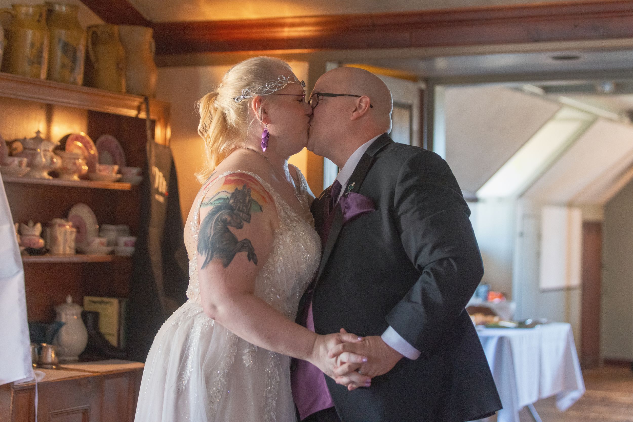 A romantic wedding moment captured during a first dance in a rustic indoor venue with warm lighting.