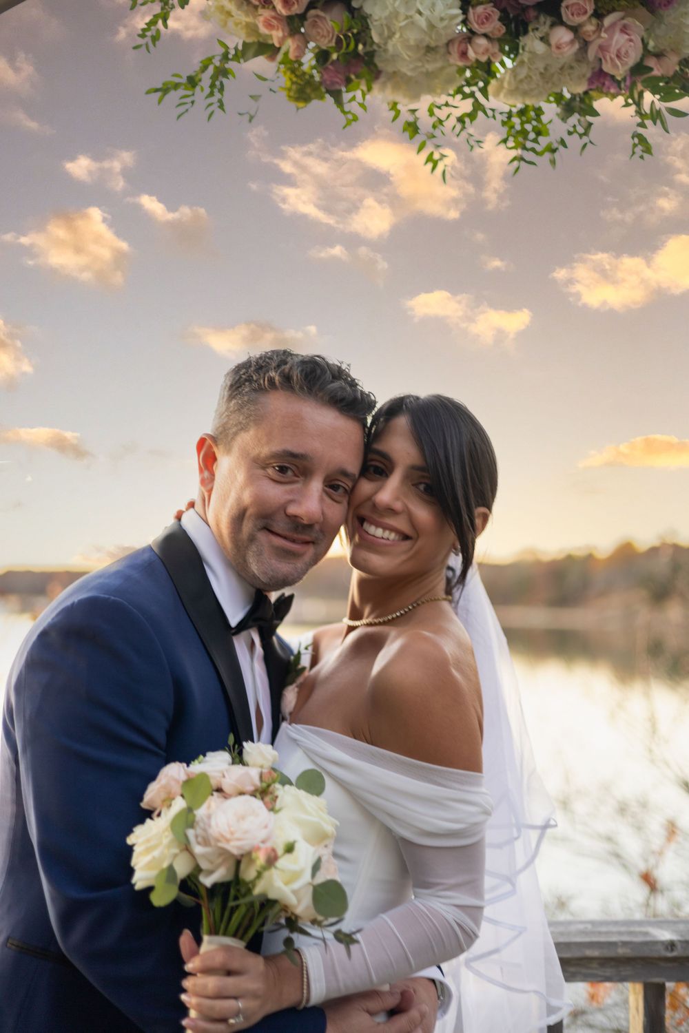 A romantic sunset wedding photoshoot by a lake with a couple in traditional attire sharing intimate moments.