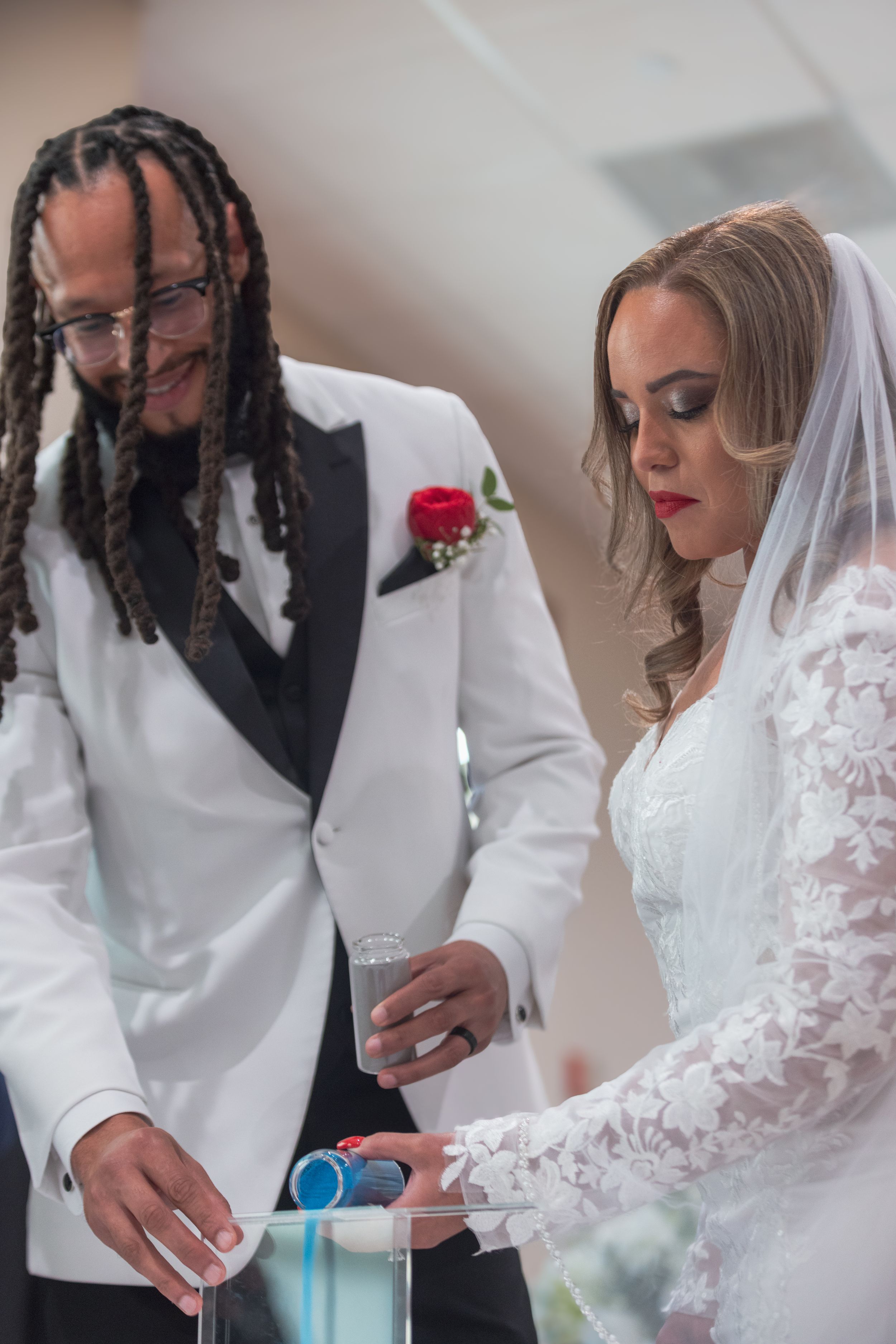 A couple in wedding attire share an intimate moment during a ceremony while holding hands and looking down.