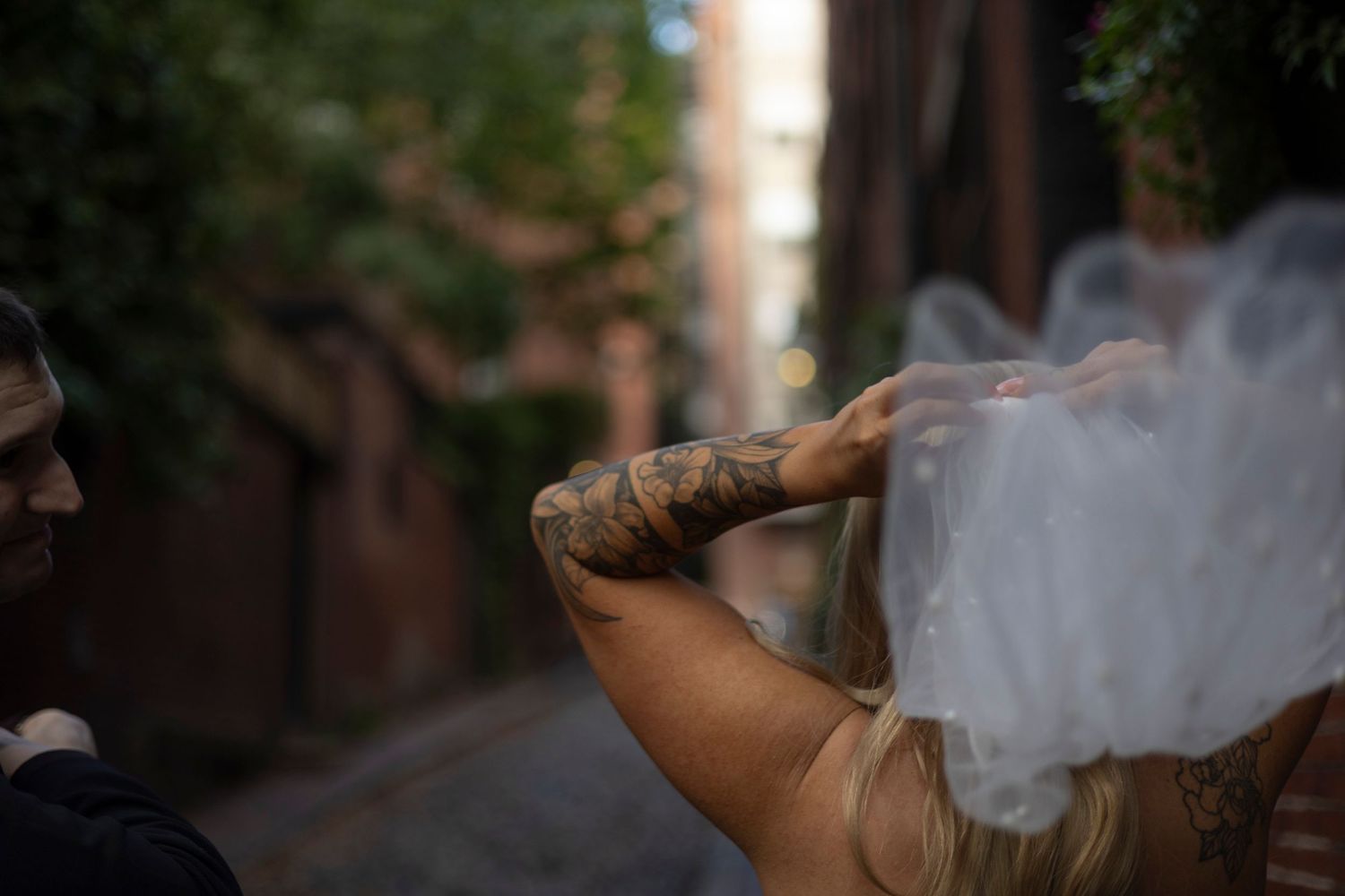 Person exhales smoke while sitting outdoors in a natural setting surrounded by trees and foliage.