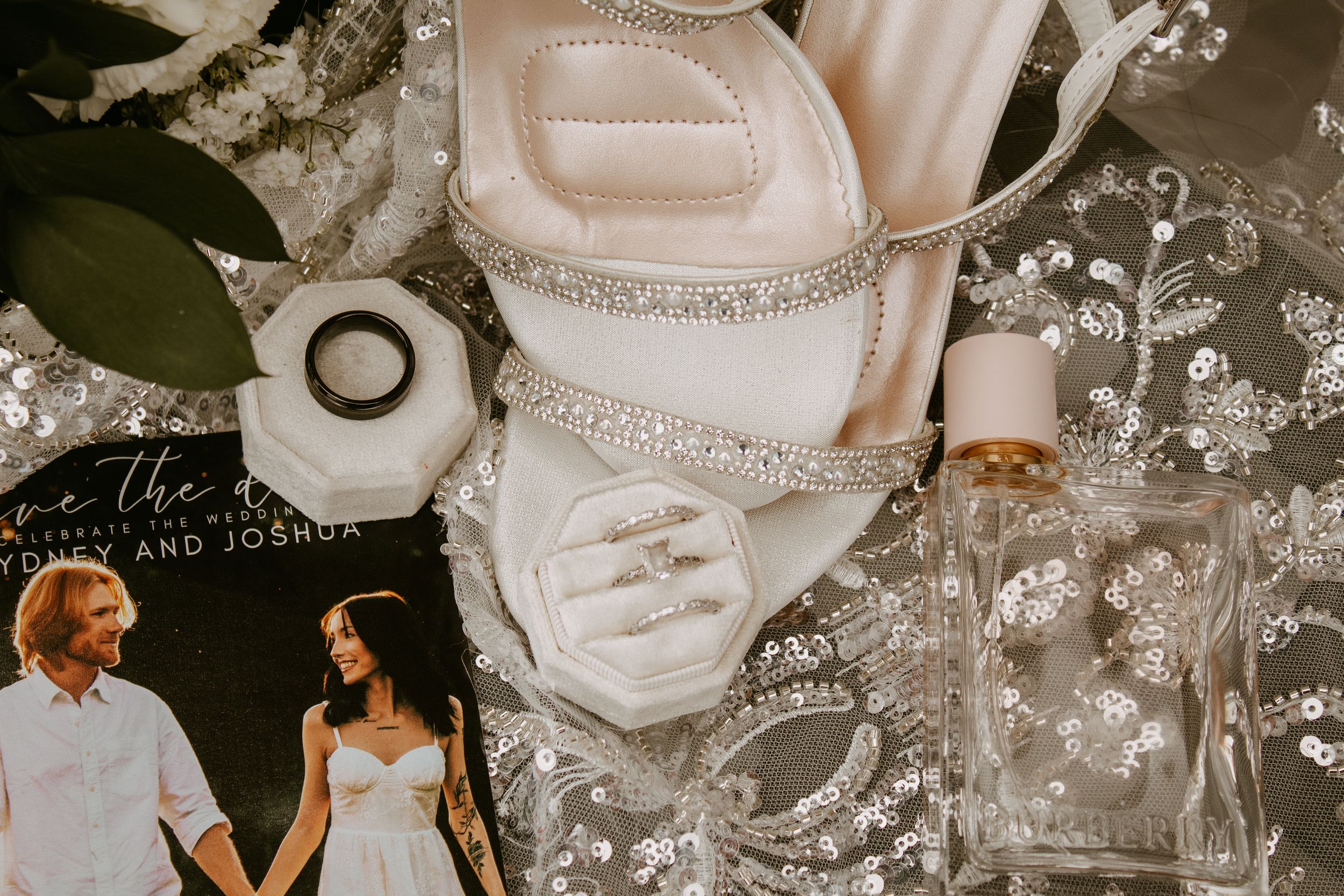Elegant wedding flat lay with rhinestone heels, rings, perfume, and save-the-date card for Amy and Joshua.