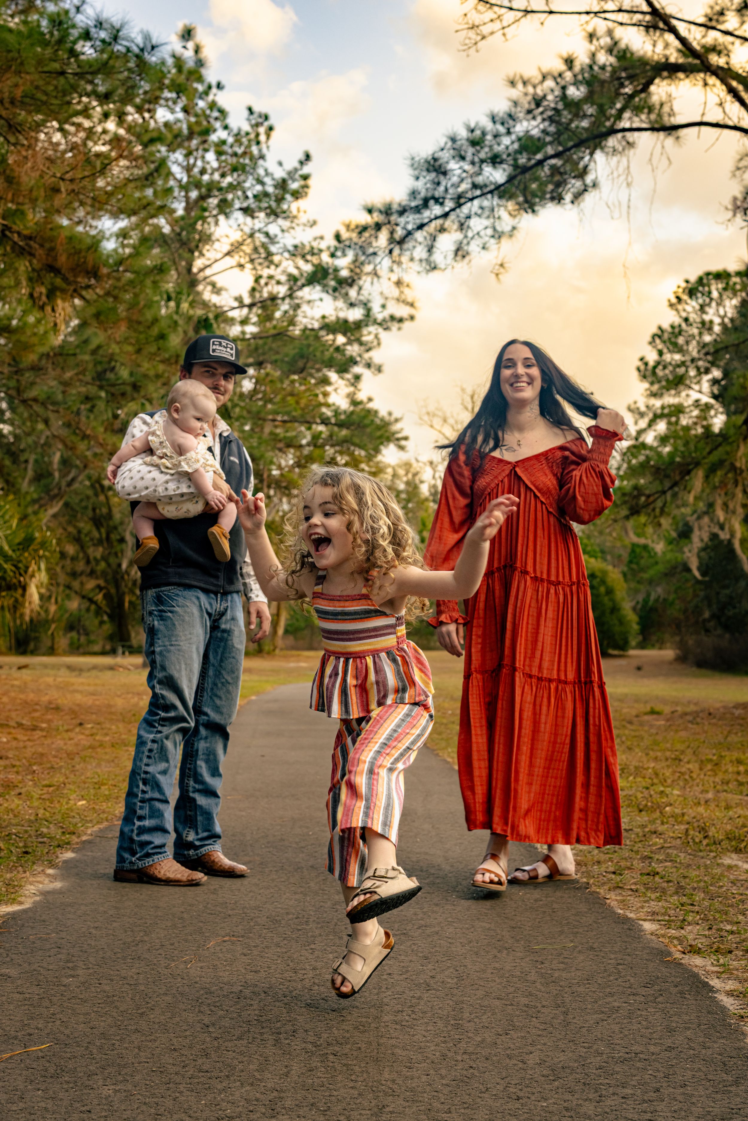 Joyful family with two children playing on a park path at golden hour.