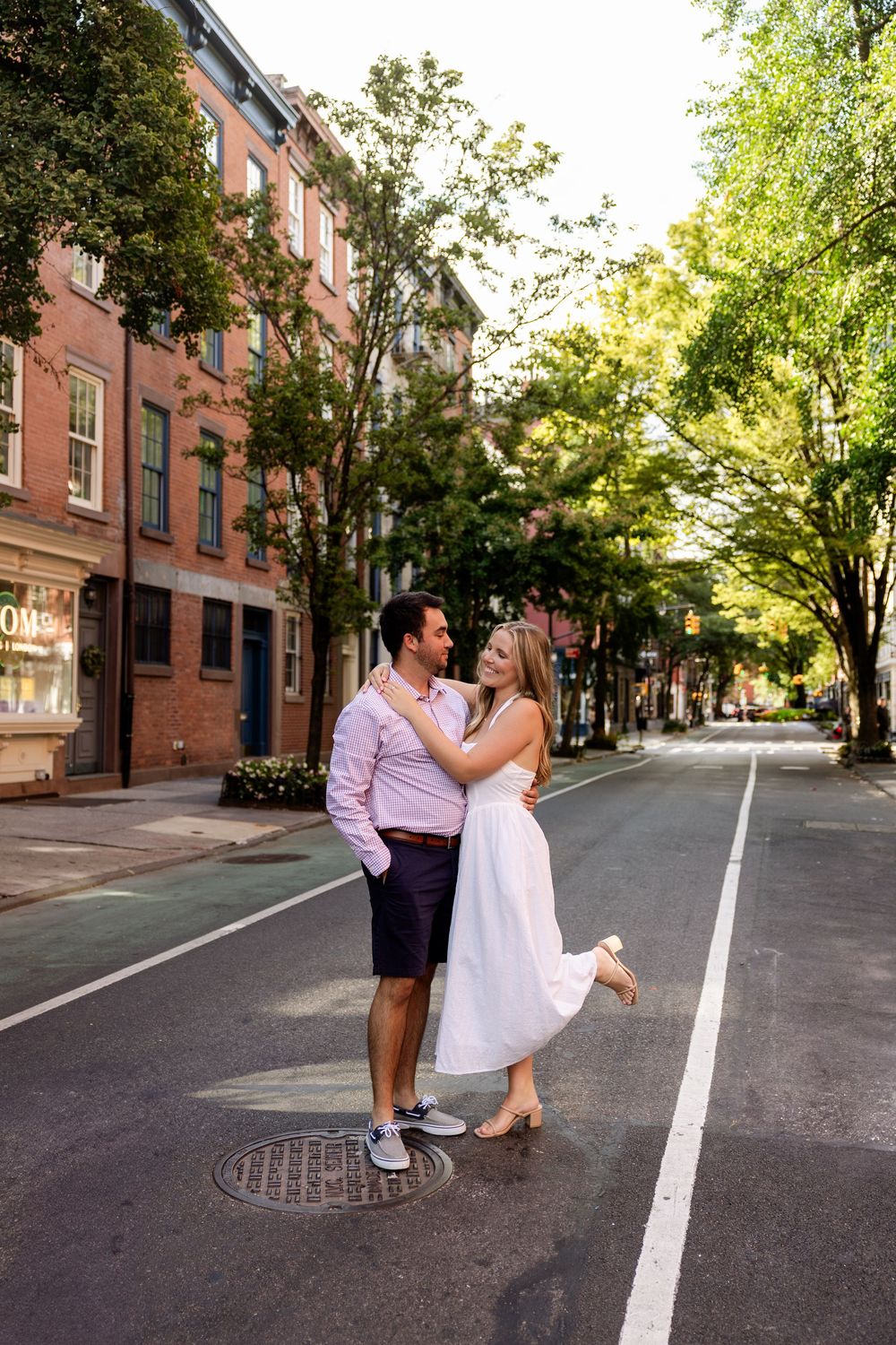 A couple sharing a romantic moment on a quiet brick-lined street in an urban neighborhood.