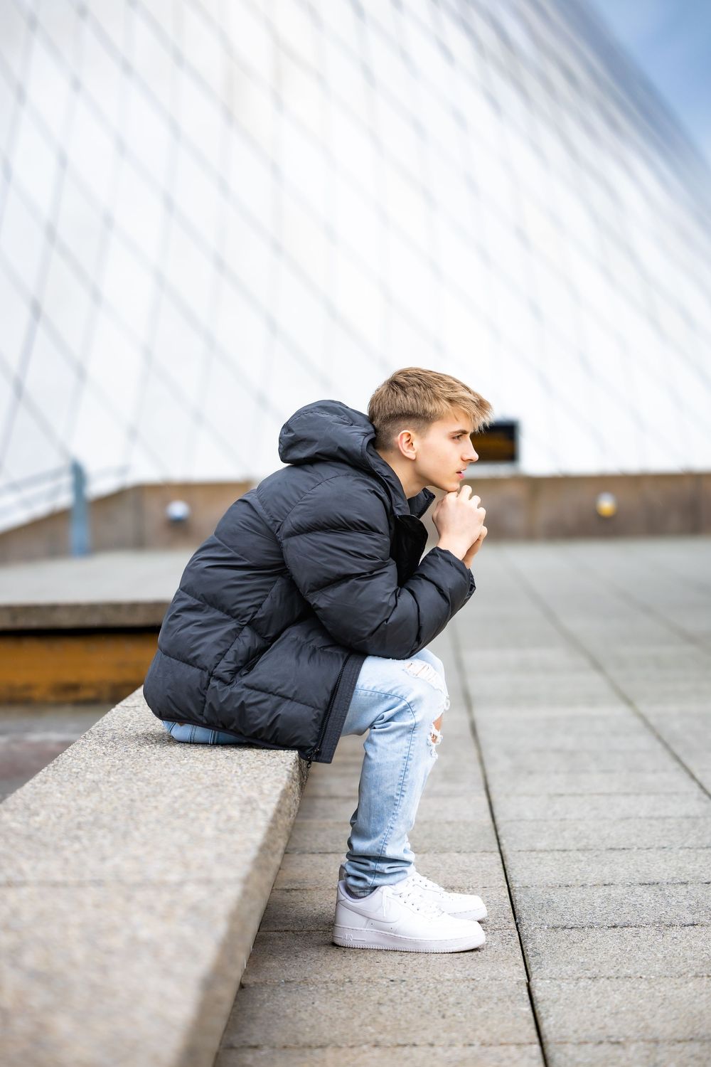 A sequence of four photos showing someone in a black jacket and jeans crouching down to examine something on concrete steps.