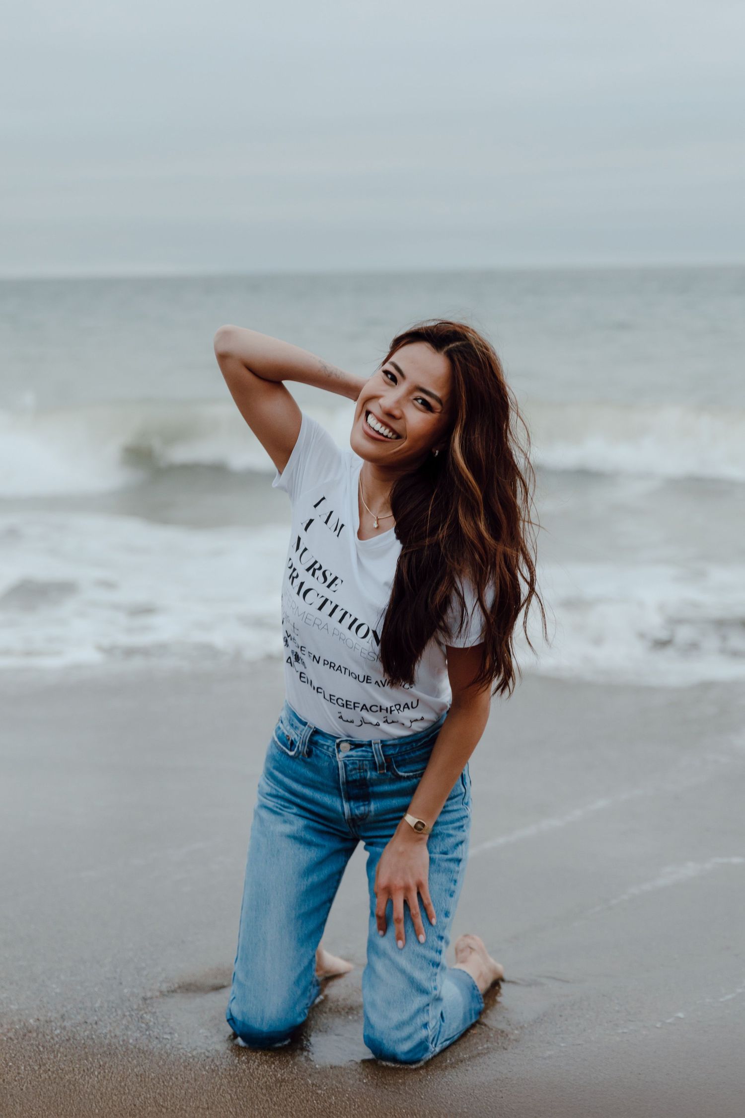 College graduate poses on Baker Beach wearing a "Nurse Practitioner" outfit for her grad session.