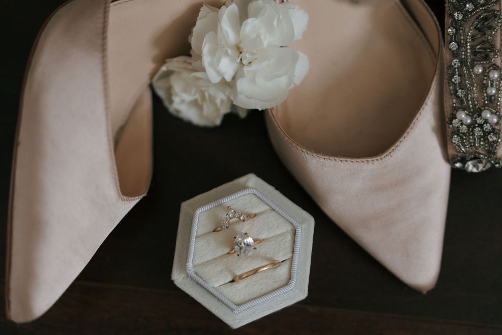Elegant bridal shoes and accessories including white heels and sparkly jewelry arranged on a dark surface.