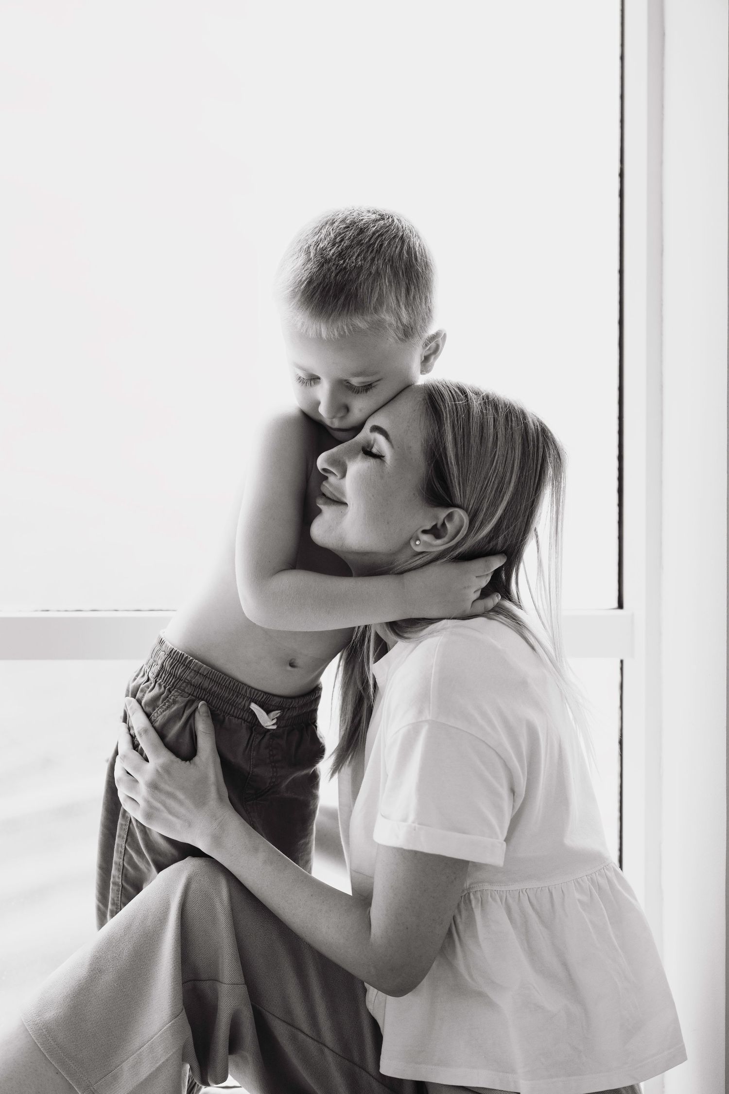 Emotional black and white family portrait captured in natural window light