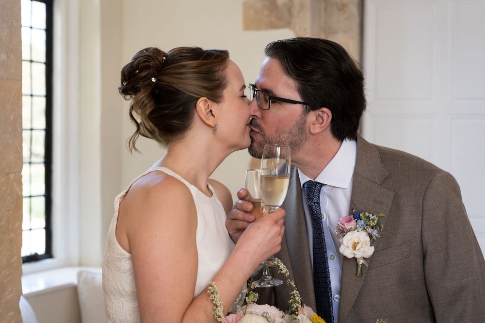 Bride and groom sharing a kiss while holding champagne glasses at their wedding reception.