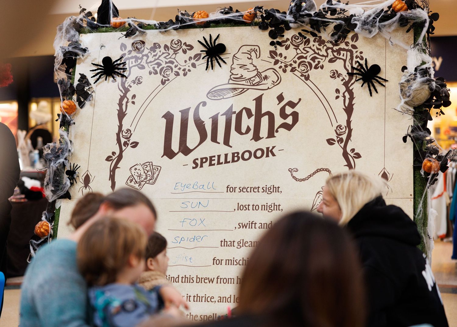 Halloween party decorations with spooky black spiders and witch's spell book displayed on a festive table setting.