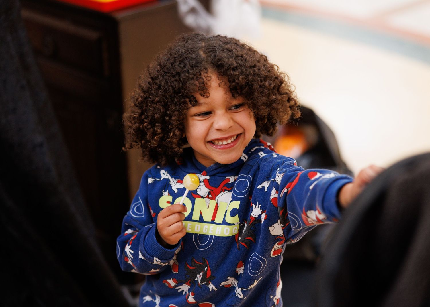 Child wearing blue dinosaur pajamas plays and smiles during an engaging moment.