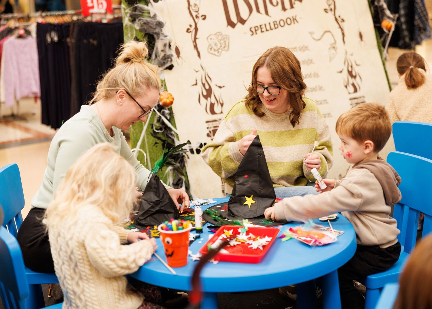 Children sit at colorful tables during a birthday party celebration with decorations and snacks.