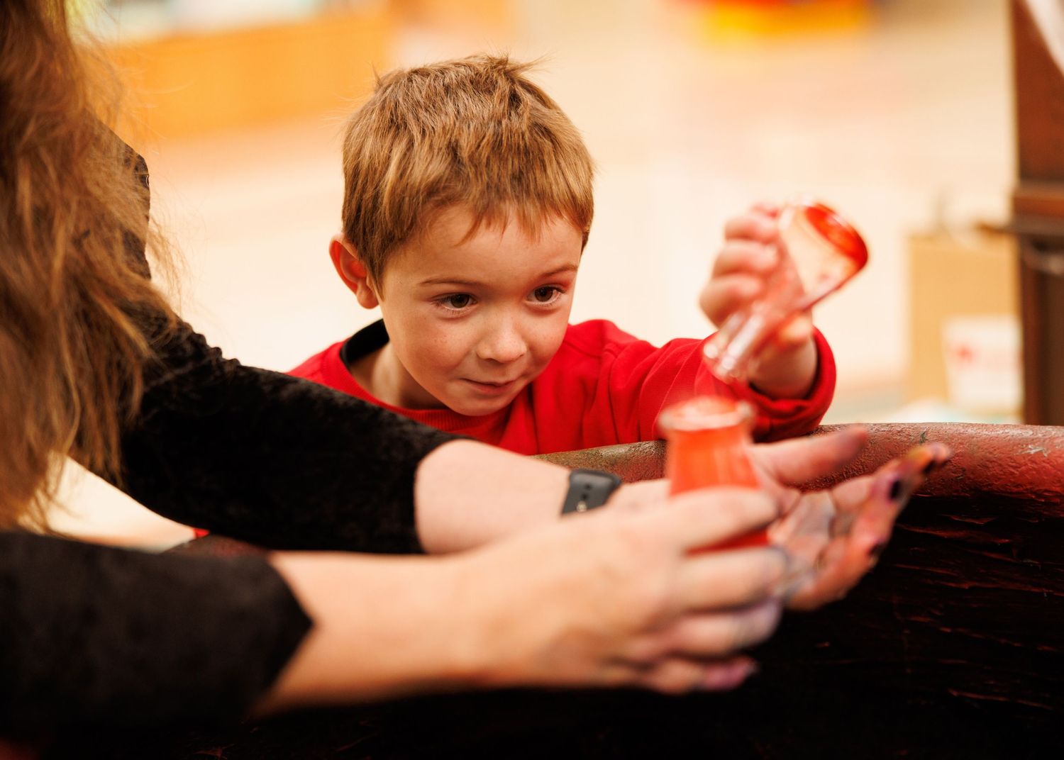 A sequence of hands passing a small red object across multiple frames in warm lighting.