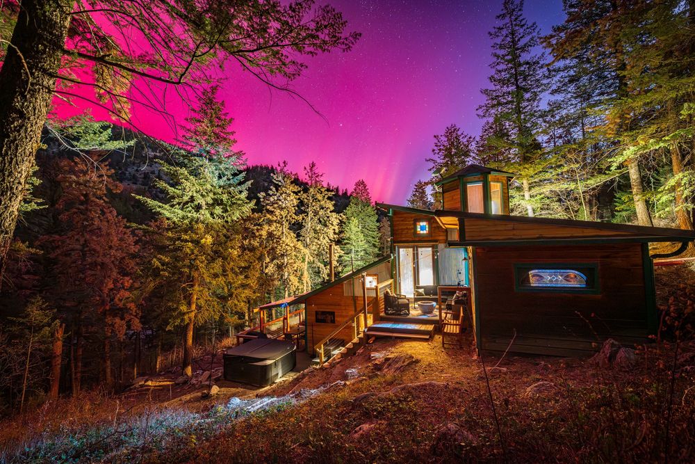 Northern lights glowing above Prospector's Pine cabin by Denver Hospitality, Travel & Tourism photographer Captain Colorado Photography.