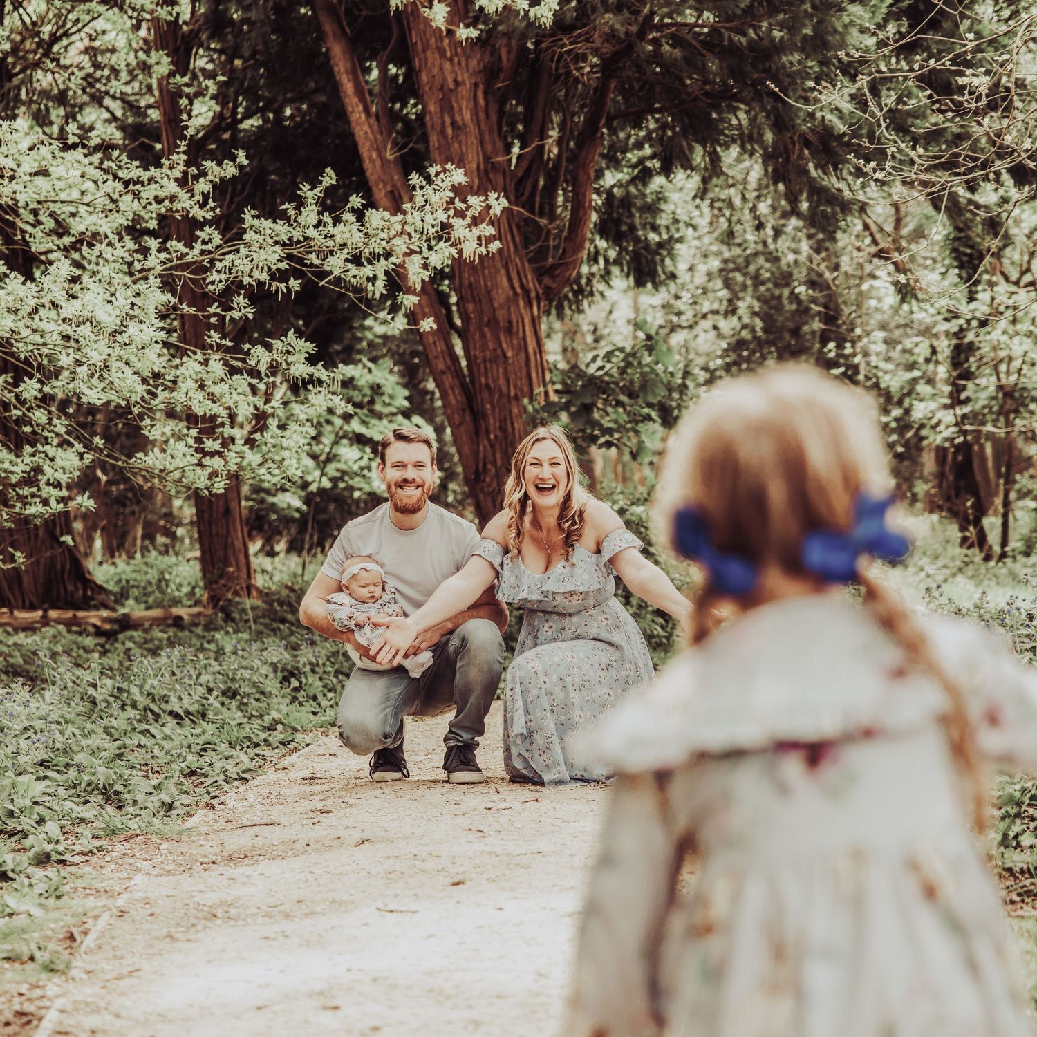 Child running towards parents during a relaxed outdoor family photoshoot, capturing natural movement and genuine connection.