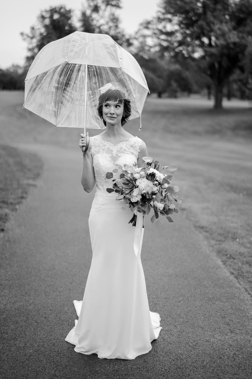Wedding portrait of bride with umbrella standing in the rain.
