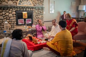 Group of people gathered in a cozy living room with stone walls for a social gathering or meeting.
