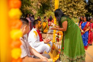 Traditional Indian wedding ceremony with turmeric ritual taking place outdoors during golden hour.