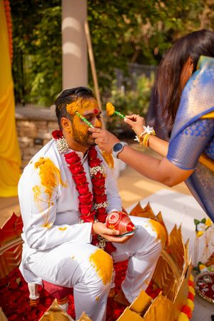 Traditional Indian Haldi ceremony with turmeric paste being applied during a pre-wedding ritual outdoors.