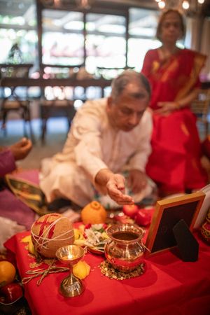 Traditional Hindu ceremonial items and offerings arranged on red cloth during a religious ritual.