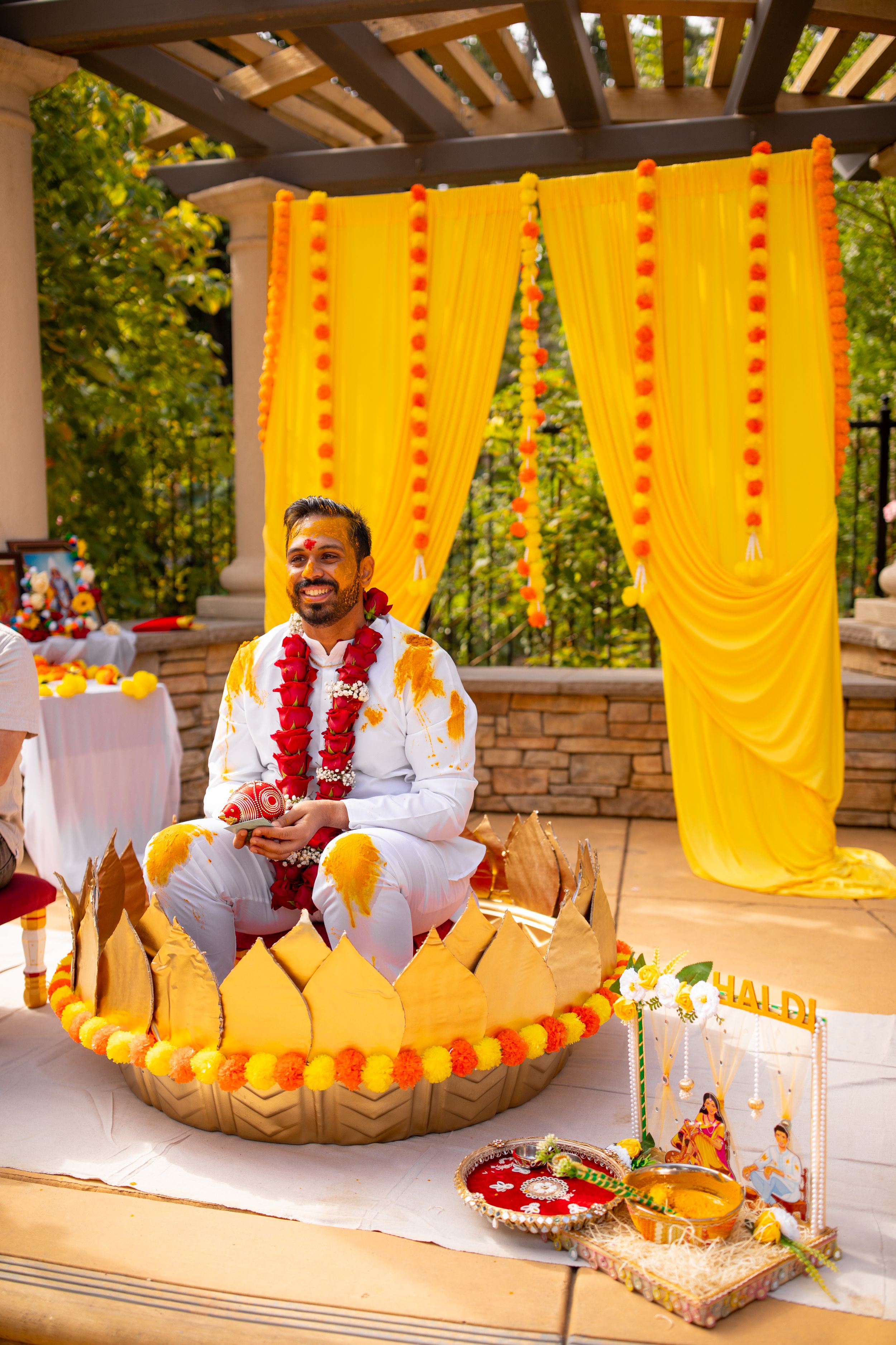 Traditional Indian wedding ceremony setup with bright yellow drapes and decorative elements on an outdoor patio.