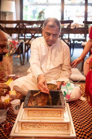 Artisan carving intricate patterns into a decorative wooden panel on a checkered table surface.