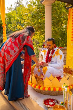 People in traditional dress gather around a table decorated with orange and red fall decor at an outdoor event.