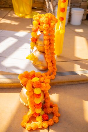 Orange marigold flower garlands cast shadows on a sunlit surface during a traditional Indian celebration or ceremony.
