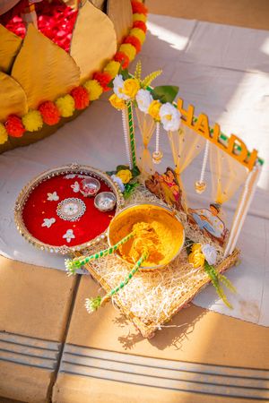 Traditional Indian wedding decorations featuring ornate red and gold plated thali plates with floral garlands and decorative elements.