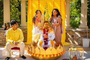 A group in traditional yellow attire sits on white steps during a cultural celebration ceremony.