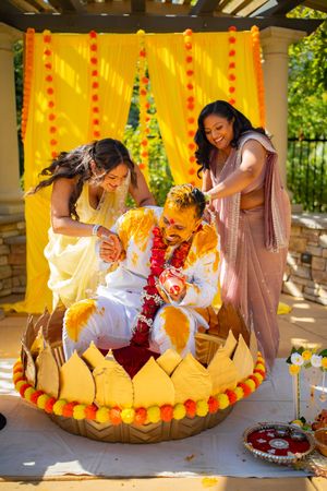 Traditional Hindu baby naming ceremony with bright yellow decorations and floral arrangements on display.