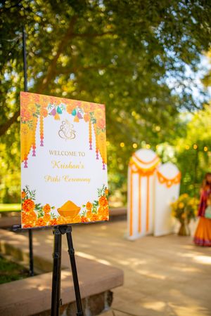 Welcome signs on display stands with orange floral designs and decorative elements at an outdoor event.