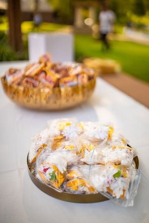 Wrapped party favors or treats arranged neatly on silver platters at an outdoor celebration.