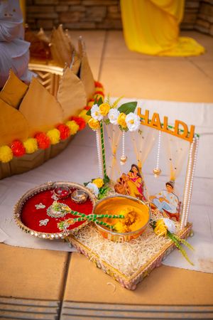 Decorative Hindu prayer thali plates adorned with flowers, candles and traditional items for a religious ceremony.