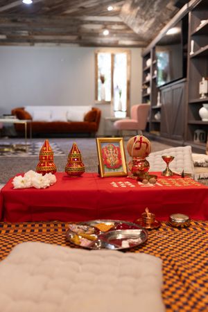 Traditional Indian wedding decorations with red fabric and ornate brass items displayed on a checkered tablecloth.