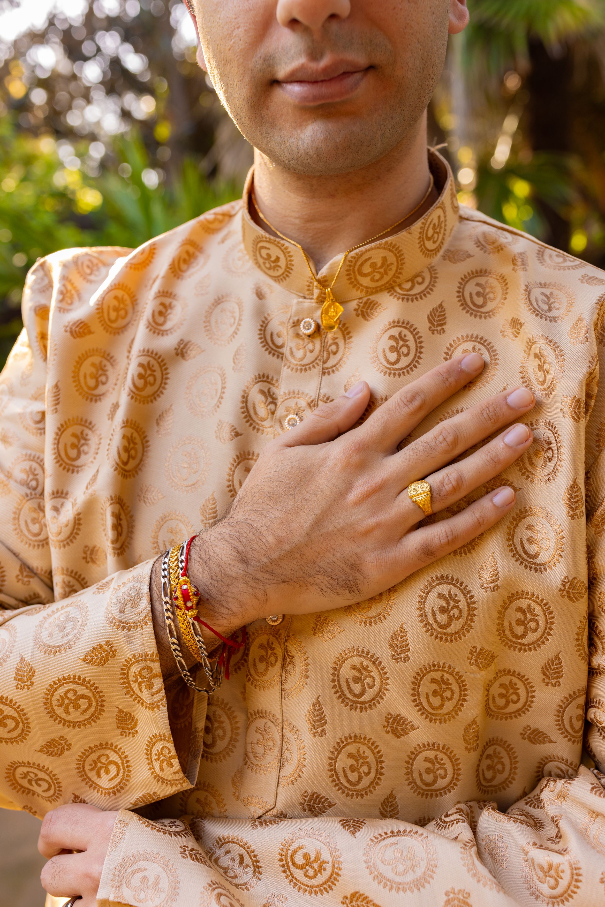 Close-up of traditional Indian wedding attire showing gold paisley patterns on beige fabric.