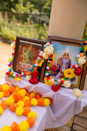 A memorial display with colorful marigold flowers and photo frames decorated with vibrant garlands.