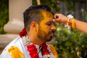 Traditional Hindu ceremony showing turmeric and red powder being applied during a ritual celebration.