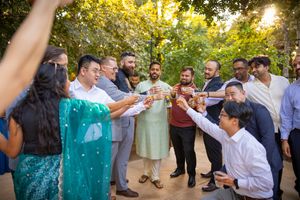 Wedding guests dance and celebrate together outdoors during a golden sunset reception.