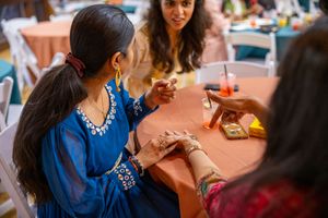 A person in a blue top sits at a table during a social gathering or event.