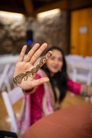 Close-up view of hands adorned with intricate henna designs at a traditional celebration.
