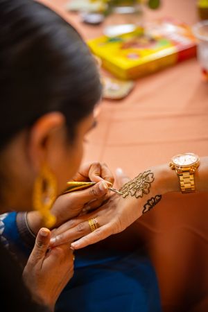 Close-up view of hands examining delicate jewelry pieces on a warm-toned wooden surface.