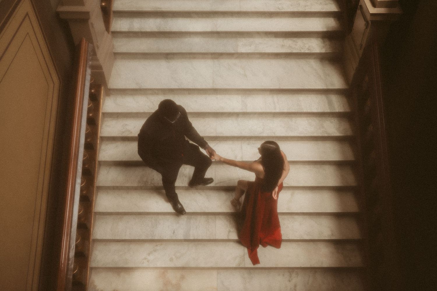 Indiana Couples Storytelling Photographer / A couple in contrasting black and red outfits on marble stairs in a dreamy, vintage-style image.