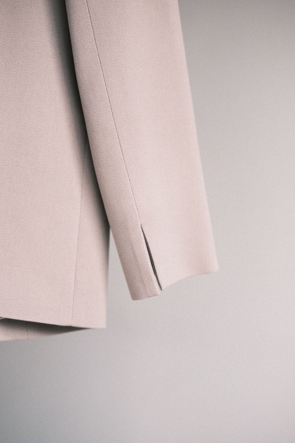 A series of minimalist photographs showing the curved edges and folds of light beige fabric or paper against a gray background.