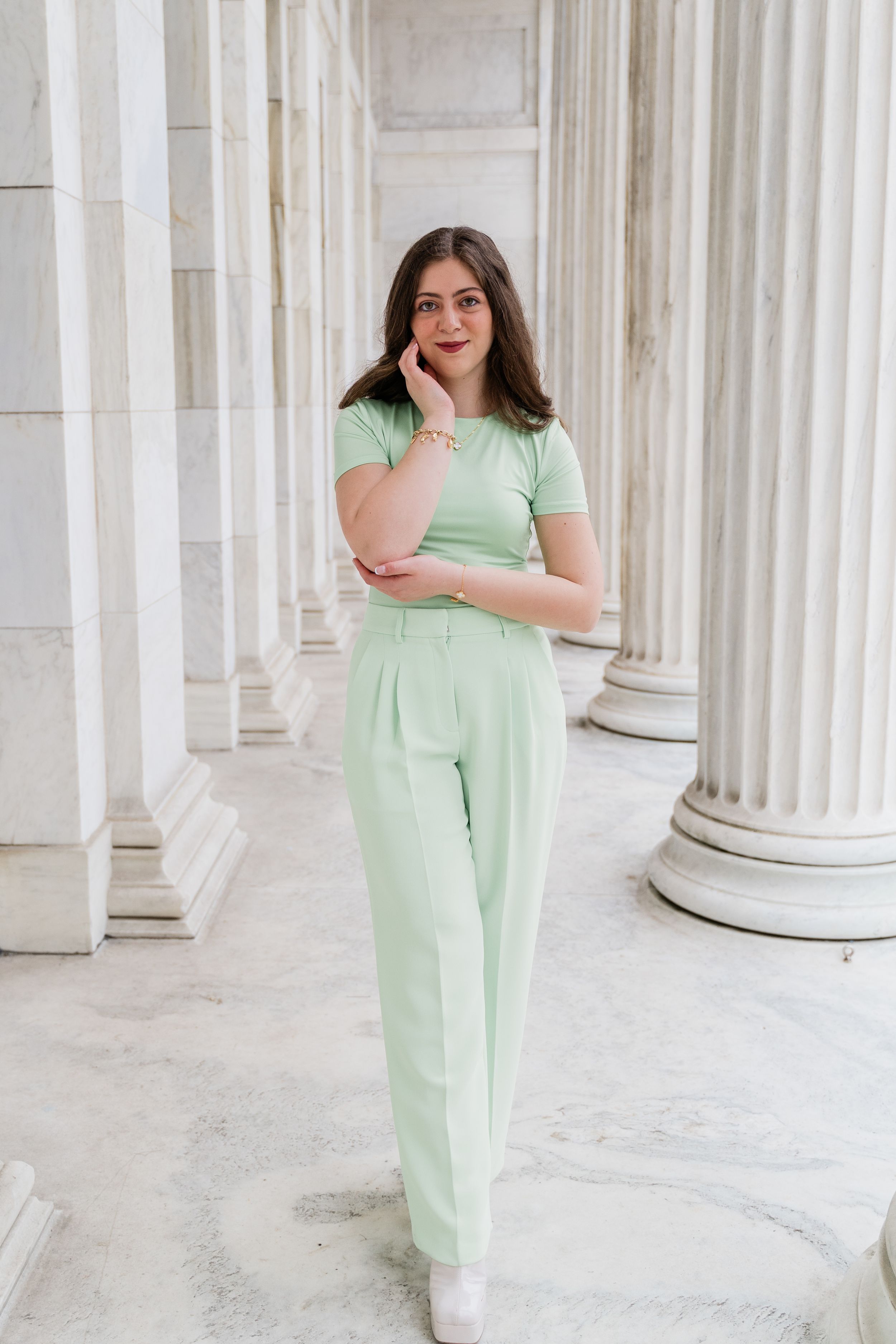 Person wearing mint green loungewear poses elegantly among white classical columns in an architectural setting.