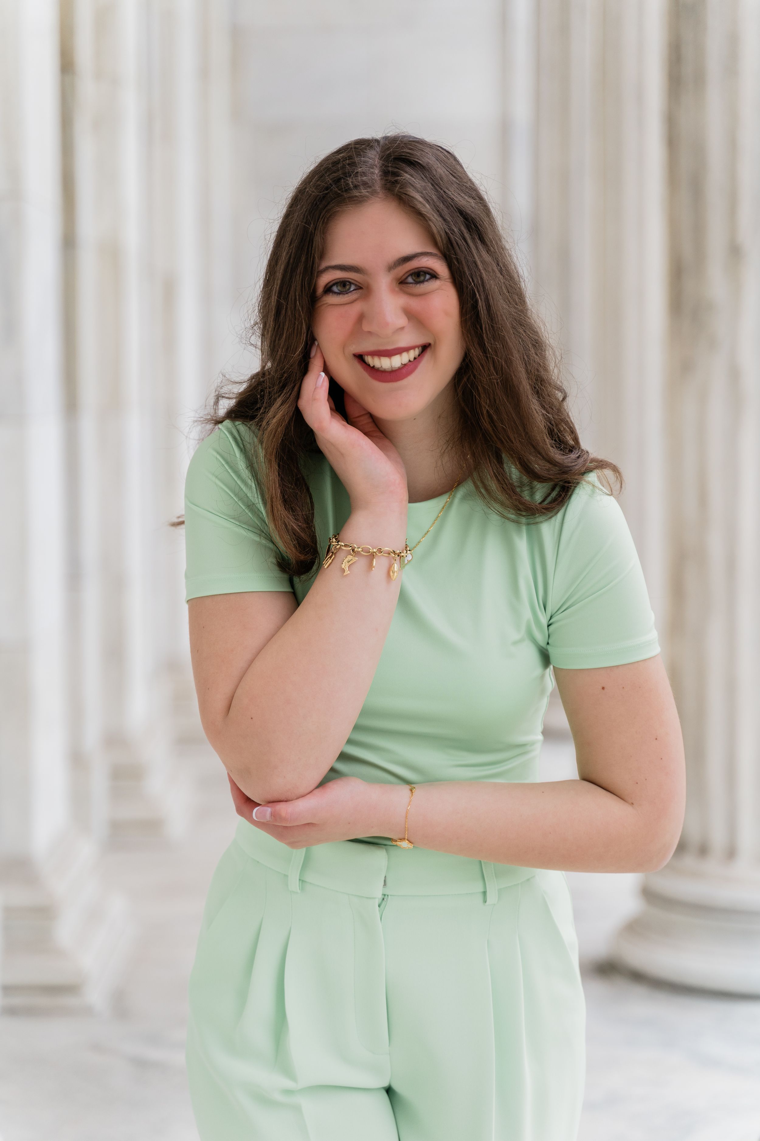 A person in a mint green outfit poses and laughs against a white columned backdrop in a four-photo series.