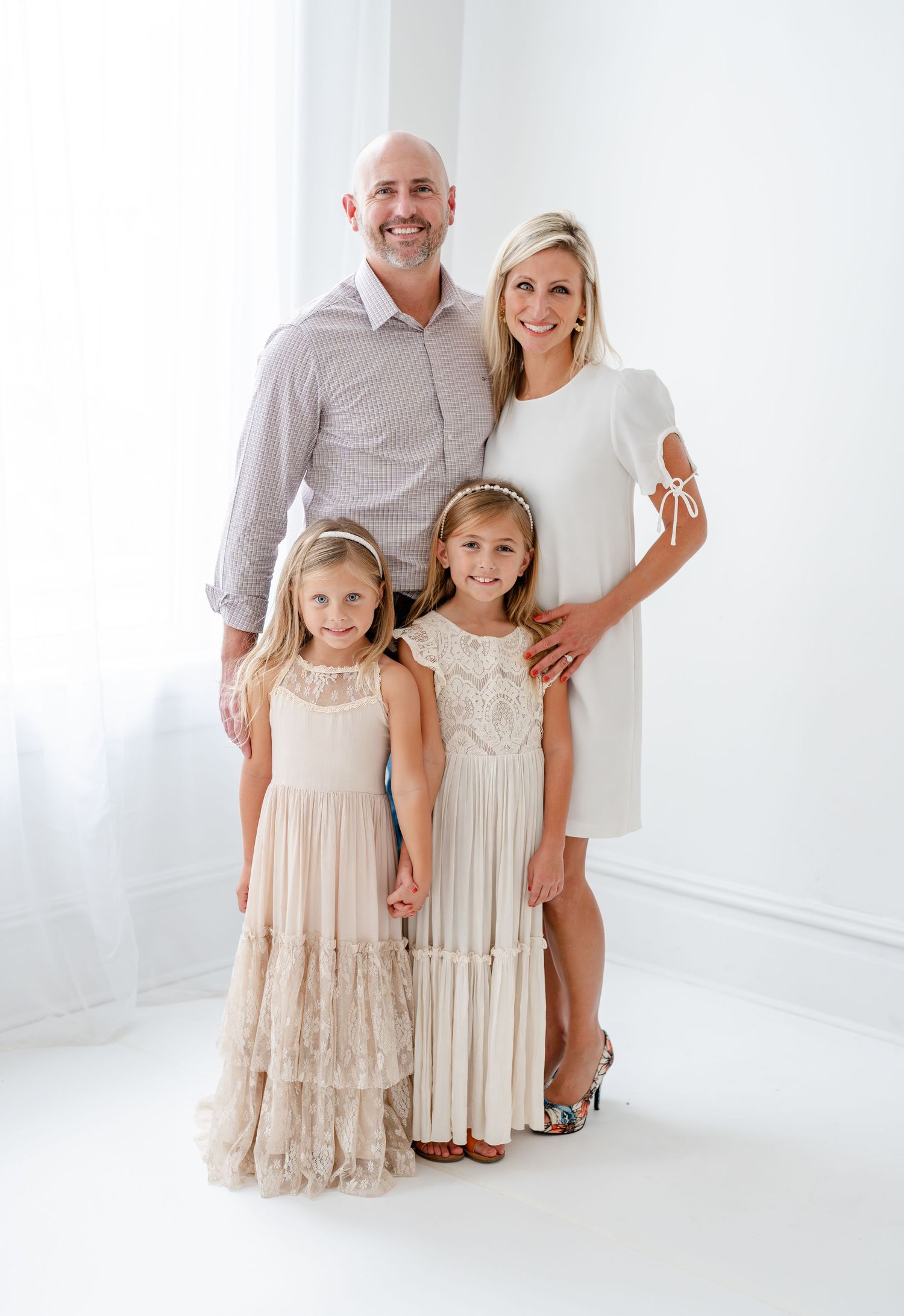 A tender moment shared between parent and child in white dresses sitting together on a light wooden floor.