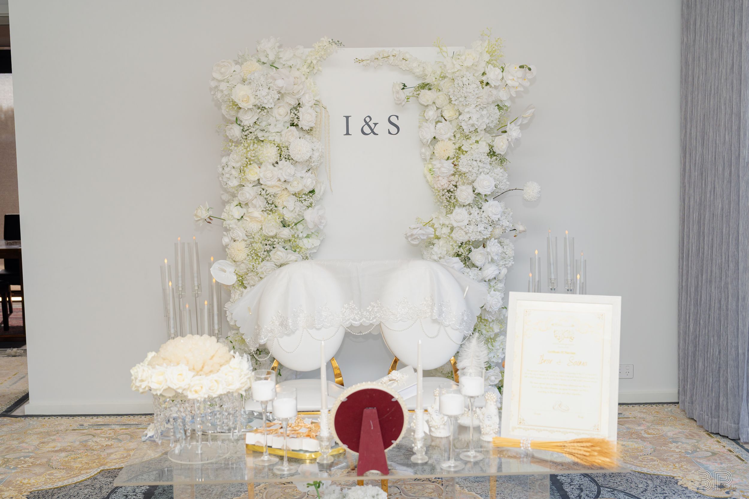 Elegant wedding reception table settings with white floral centerpieces and crystal glassware in a modern venue.