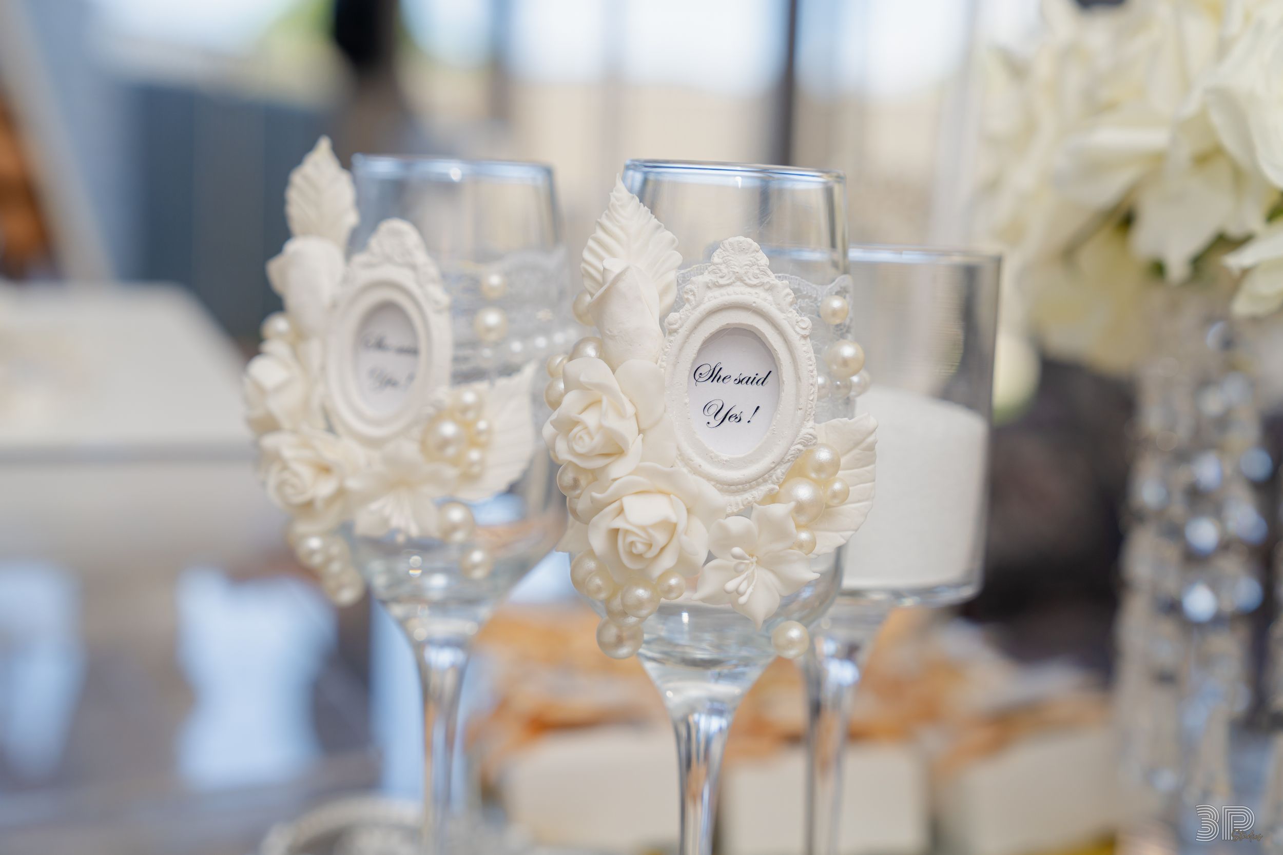 White hydrangea centerpieces and crystal stemware adorn wedding reception tables with soft gray decor.