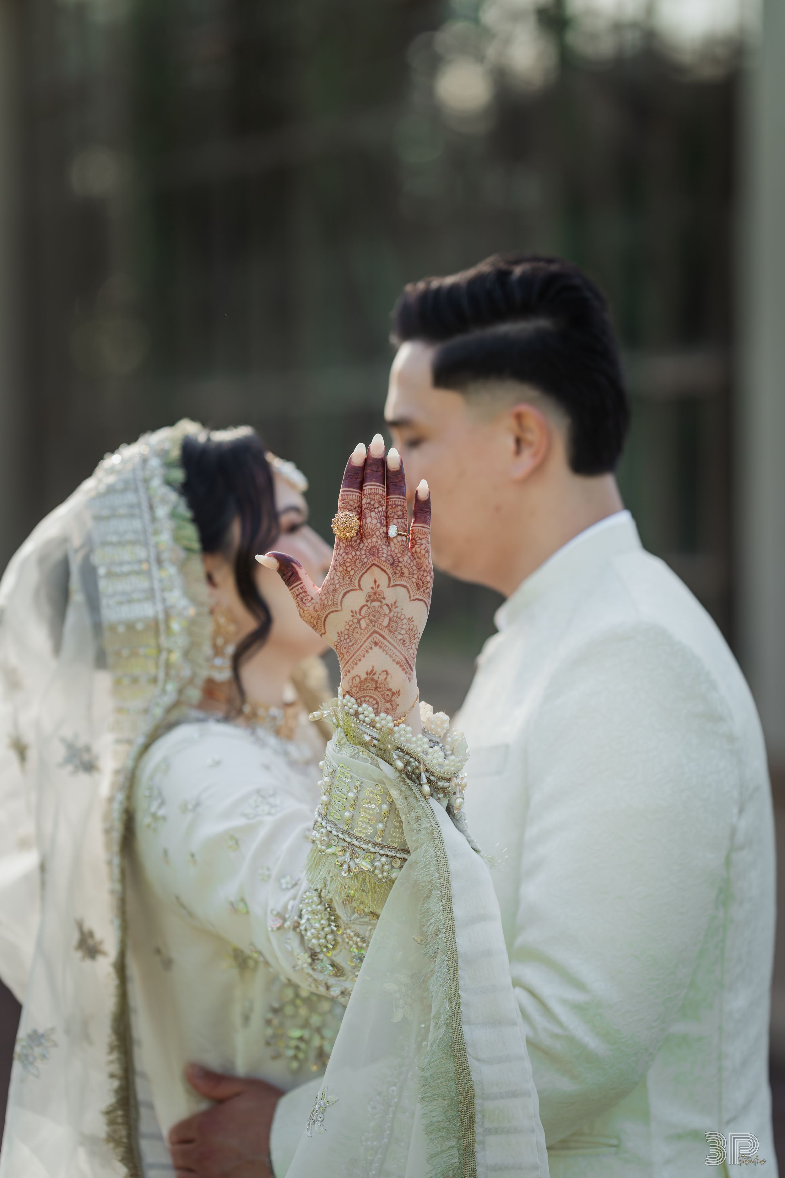 Wedding couple in traditional white attire sharing an intimate moment outdoors.